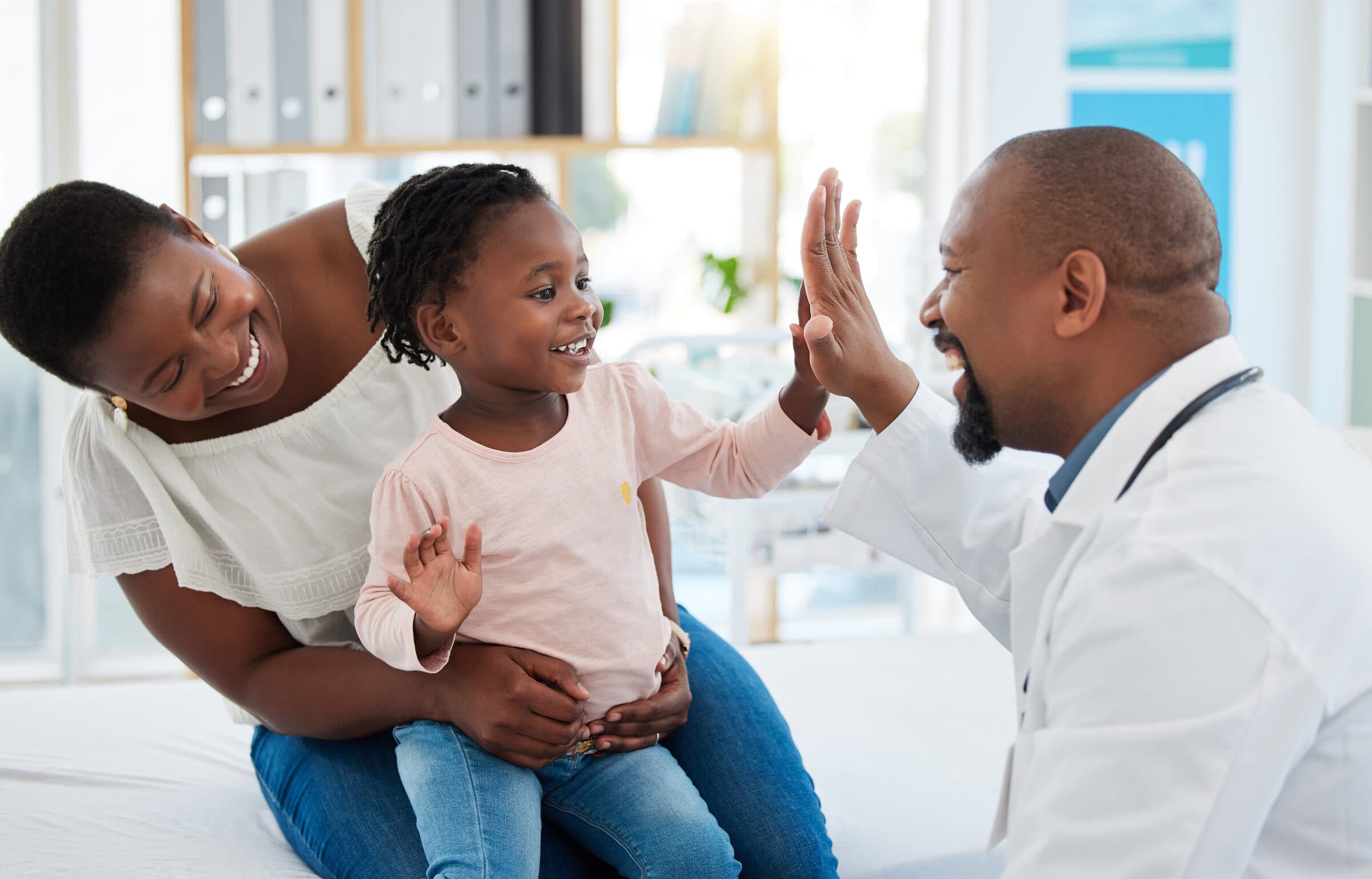 Doctor giving a young patient a high five during a check-up